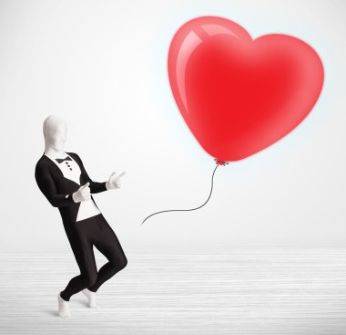 Morpsuit giyip balon şeklinde bir kalbe bakan yakışıklı bir adam.