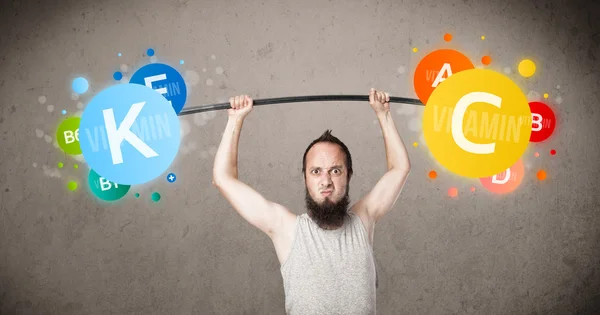 Skinny guy lifting colorful vitamin weights — Stock Photo, Image