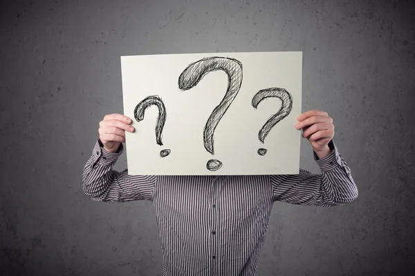 Businessman holding a paper with question marks in front of his — Stock Photo, Image