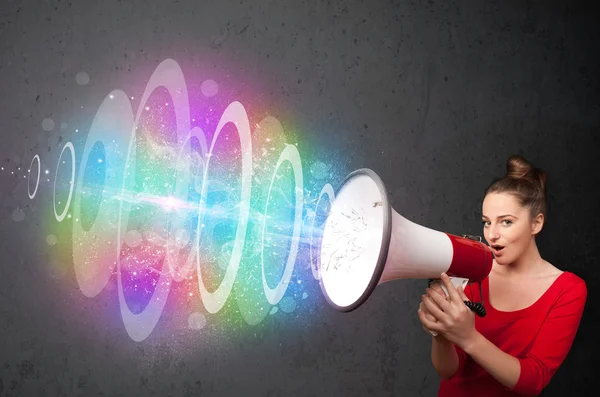 Young girl yells into a loudspeaker and colorful energy beam com — Stock Photo, Image