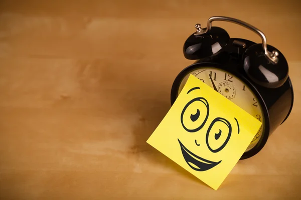 Post-it note with smiley face sticked on clock — Stock Photo, Image