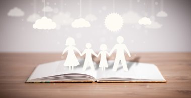 Ailenin karton figürleri açık bir kitabın üzerinde.