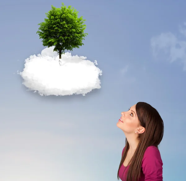 Jong meisje wijzend op een groene boom op de top van een witte wolk — Stockfoto