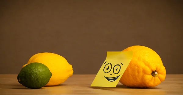 Lemon with post-it note watching at citrus fruits — Stock Photo, Image
