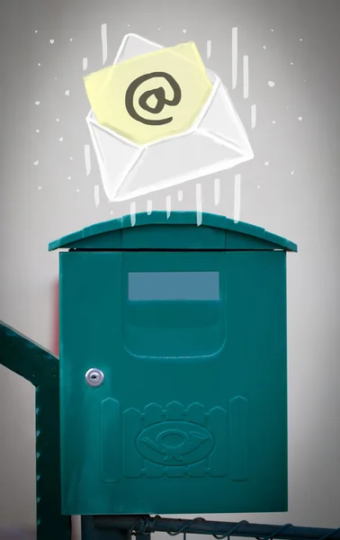 Envelope with email sign dropping into mailbox — Stock Photo, Image