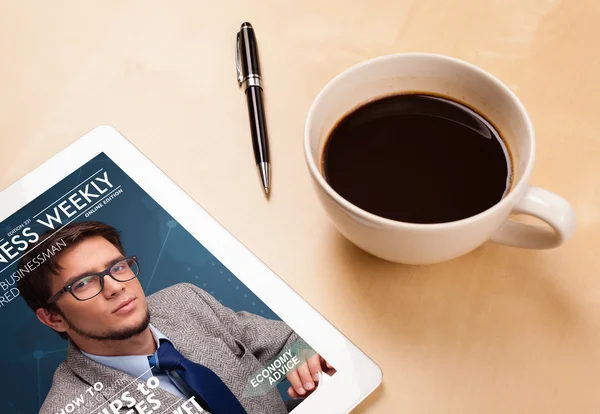 Tablet pc showing magazine on screen with a cup of coffee on a d — Stock Photo, Image