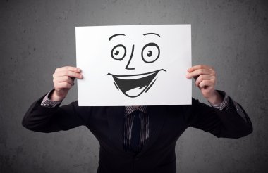 empresario sosteniendo una cartulina con cara sonriente en él en frente