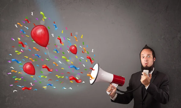 Young guy having fun, shouting into megaphone with balloons — Stock Photo, Image