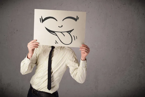 Empresario sosteniendo un papel con la cara sonriente divertido en frente de h —  Fotos de Stock