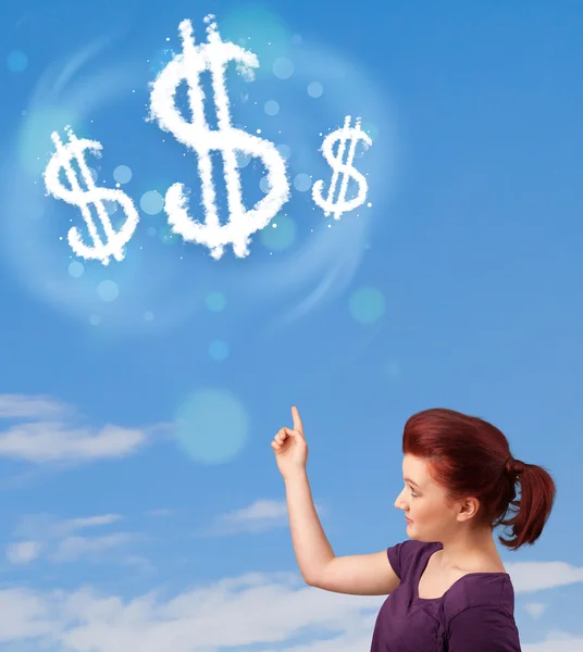 Young girl pointing at dollar sign clouds on blue sky — Stock Photo, Image