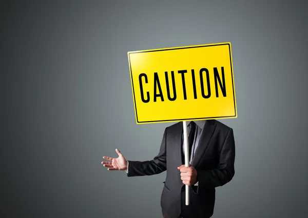 Businessman holding a caution sign — Stock Photo, Image