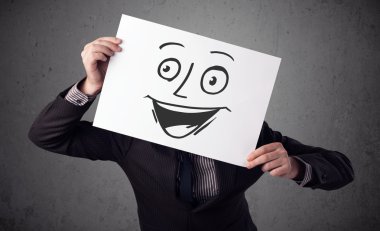 empresario sosteniendo una cartulina con cara sonriente en él en frente