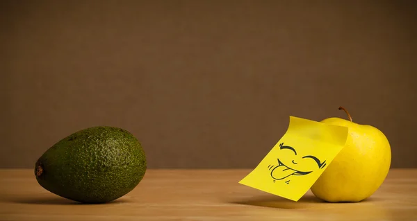 Apple with post-it note sticking out tongue to avocado — Stock Photo, Image