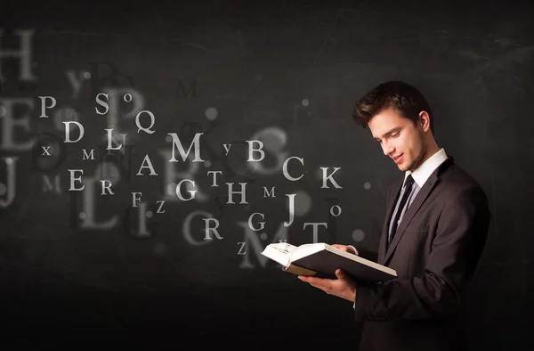 Young man reading a book with alphabet letters — Stock Photo, Image