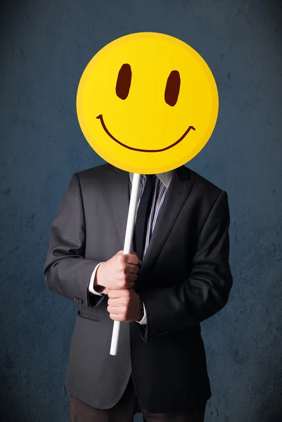 Empresário segurando um emoticon rosto sorridente — Fotografia de Stock