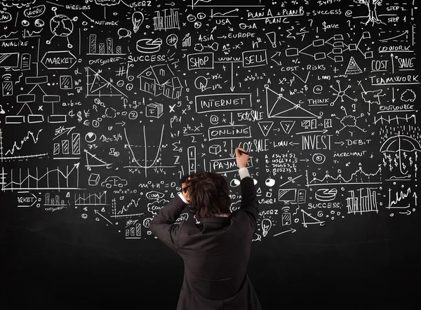 Businessman standing in front of drawn charts on a blackboard — Stock Photo, Image
