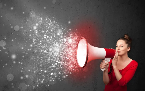 Woman shouting into megaphone and glowing energy particles explo — Stock Photo, Image