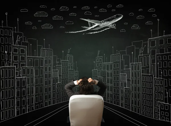 Businessman sitting in front of a cityscape drawing on a chalkbo — Stock Photo, Image