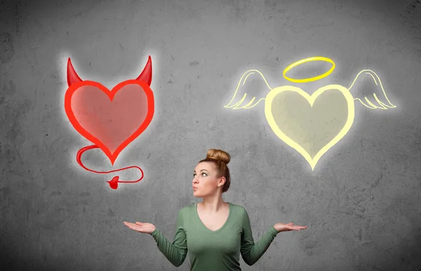 Woman standing between the angel and devil hearts — Stock Photo, Image