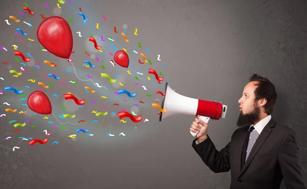 Chico joven divirtiéndose, gritando en megáfono con globos — Foto de Stock