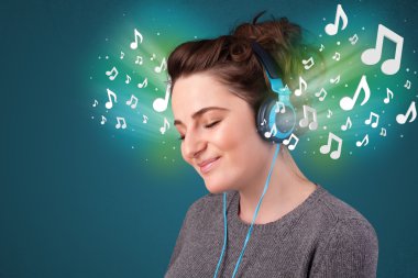 Kulaklıklı genç bir kadın müzik dinliyor.