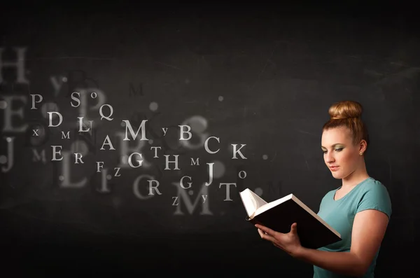 Young lady reading a book with alphabet letters — Stock Photo, Image