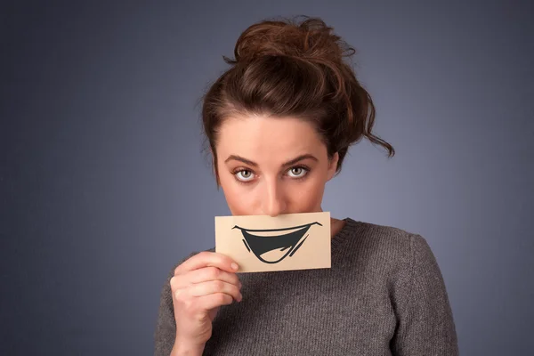 Happy cute girl holding paper with funny smiley drawing — Stock Photo, Image