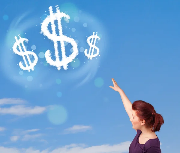 Young girl pointing at dollar sign clouds on blue sky — Stock Photo, Image