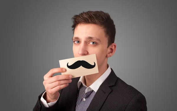 Happy businessman holding funny mustache card on his mouth — Stock Photo, Image