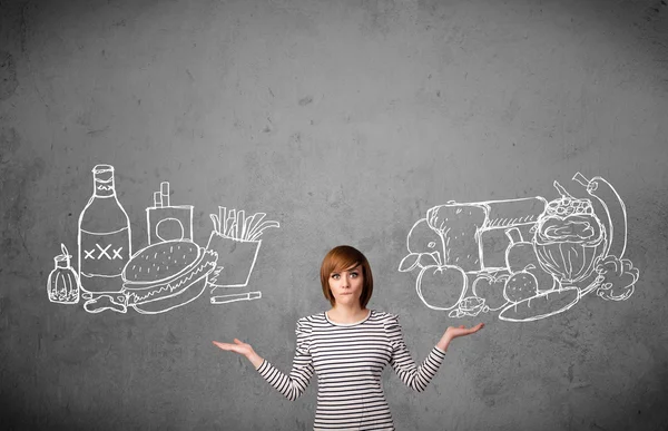 Femme debout entre les aliments sains et malsains — Photo