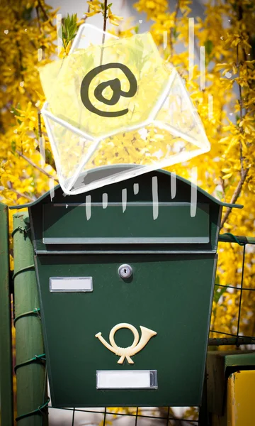 Envelope with email sign dropping into mailbox — Stock Photo, Image