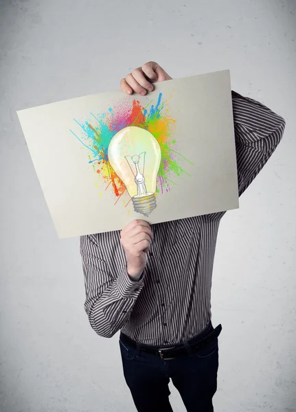 Empresario sosteniendo un cartón con salpicaduras de pintura y lightbul —  Fotos de Stock
