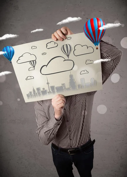 Businessman holding a cardboard with cityscape in front of his h — Stock Photo, Image