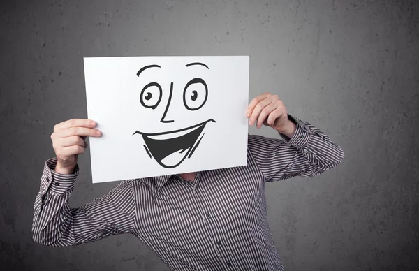 Empresário segurando um papelão com rosto sorridente na frente — Fotografia de Stock