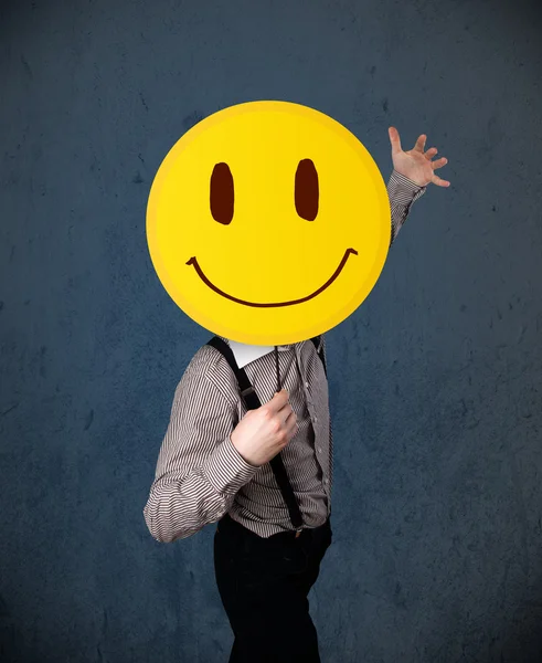 Empresario sosteniendo un emoticono sonriente — Foto de Stock