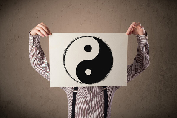 Businessman holding a paper with a yin-yang on it in front of hi