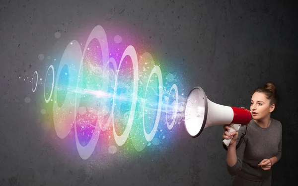 Young girl yells into a loudspeaker and colorful energy beam com — Stock Photo, Image