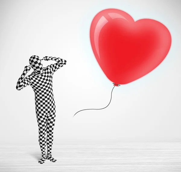 Lindo tipo en traje de cuerpo morpsuit mirando un corazón en forma de globo —  Fotos de Stock