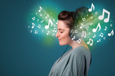 Kulaklıklı genç bir kadın müzik dinliyor.