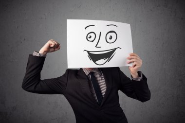 empresario sosteniendo una cartulina con cara sonriente en él en frente