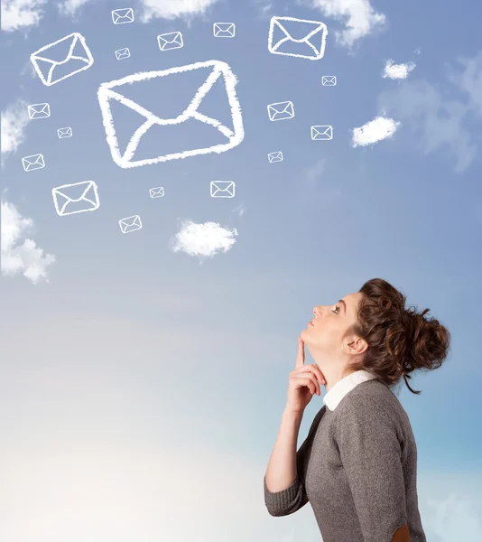 Young girl looking at mail symbol clouds on blue sky — Stock Photo, Image