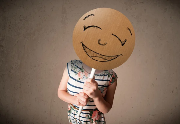 Young woman holding a smiley face board — Stock Photo, Image