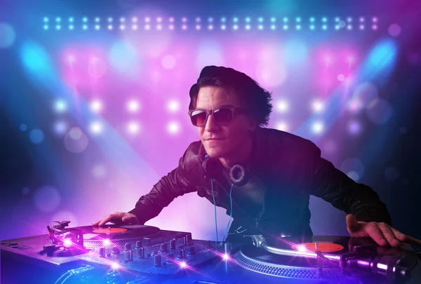 Disco jockey mezcla de música en los tocadiscos en el escenario con luces y —  Fotos de Stock