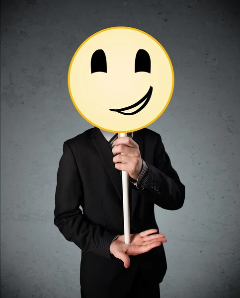 Empresario sosteniendo un emoticono sonriente — Foto de Stock