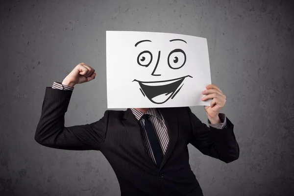 Empresário segurando um papelão com rosto sorridente na frente — Fotografia de Stock