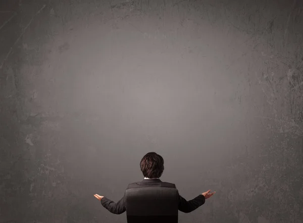 Businessman sitting in front of a wall with copy space — Stock Photo, Image