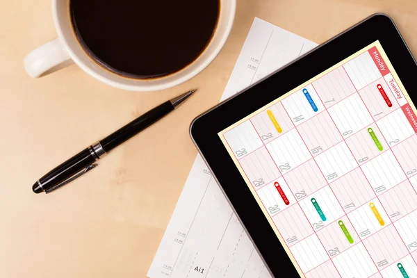 Tablet PC que muestra el calendario en la pantalla con una taza de café en una d — Foto de Stock