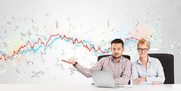 Business man and woman sitting at table with stock market graph — Stock Photo, Image