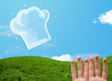 Mutlu gülen yüzlü parmaklar aşçı şapkasının resmine bakıyor.