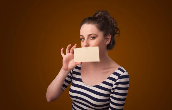 Симпатичная девушка держит белую карточку перед губами с копировальным аппаратом. — стоковое фото